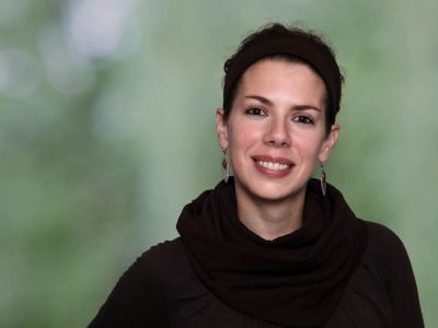 Elisabeth Alsaadi-Mauerer, die Einrichtungsleitern des Treffpunkt Pfaffenaecker - eine junge Frau in schwarzem Pullover vor grünem Hintergrund.